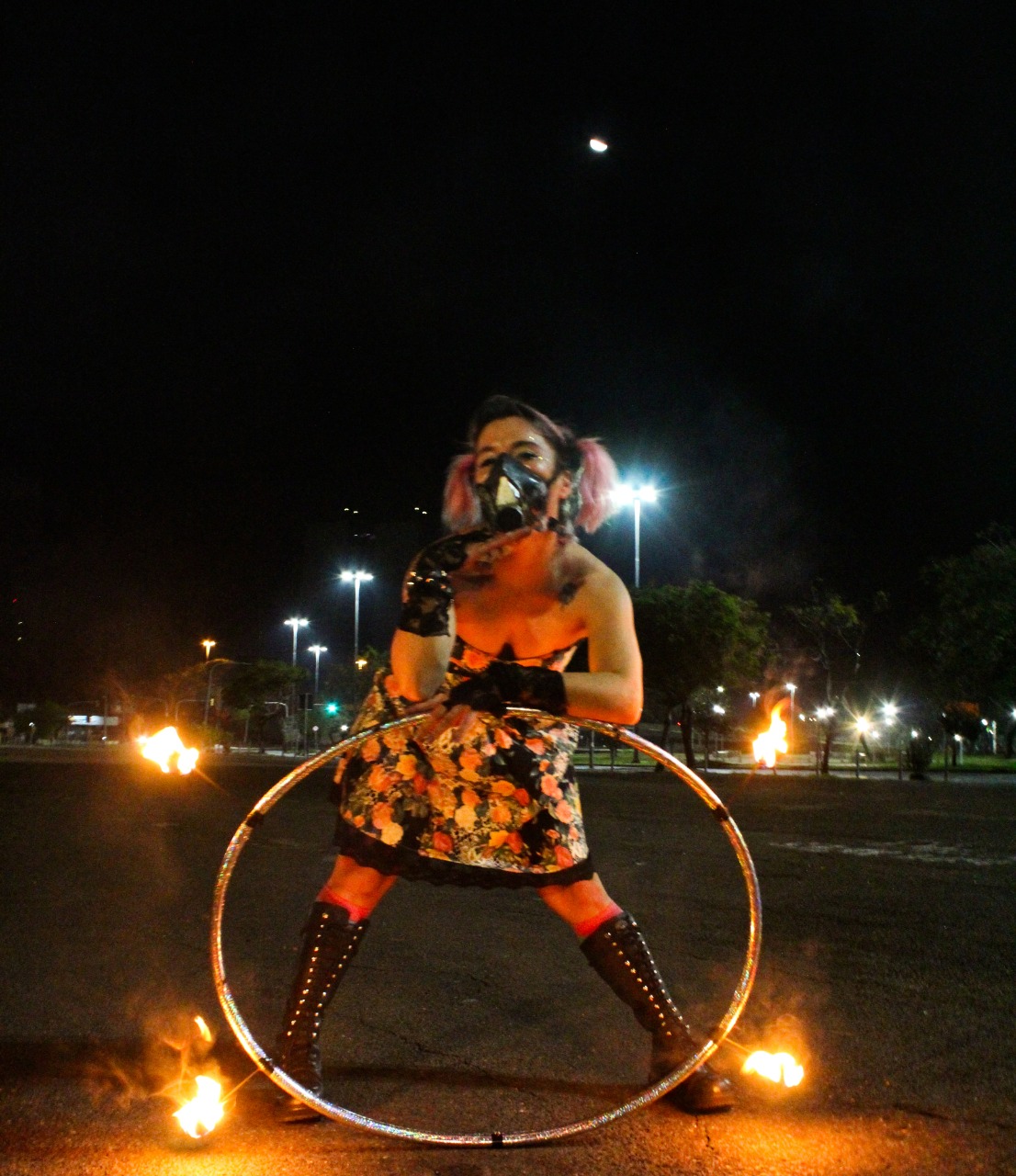 Foto da artista Jac Martinez segurando um arco com tochas de fogo.
