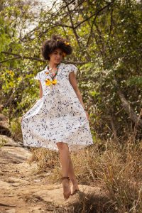Modelo veste vestido curto, branco com estampas.