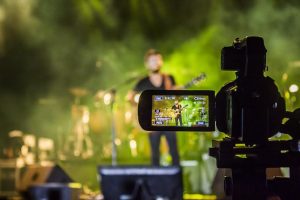 Imagem demonstra uma filmagem de uma cena com um homem e um guitarra